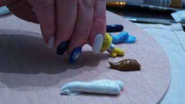 Kızlar sarı yağlı boyayı ahşap bir paletin üzerine sıkarlar.