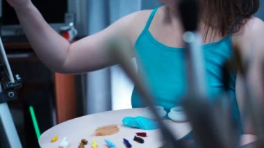 Yetenekli bir sanatçı tuval üzerinde fırçayla resim çizer. Fırçaların arkasından manzara, paletten sanatçıların yüzüne düzgün bir geçiş.