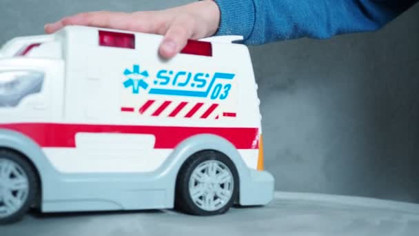 Dětská ručička si hraje se sanitkou na gauči. ambulance s nápisem sos — Stock video