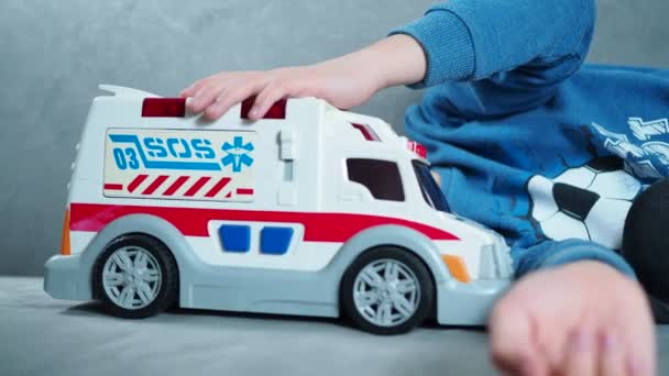 Een lachende jongen speelt met een ambulance. kinderen verbeelding is een spel — Stockvideo