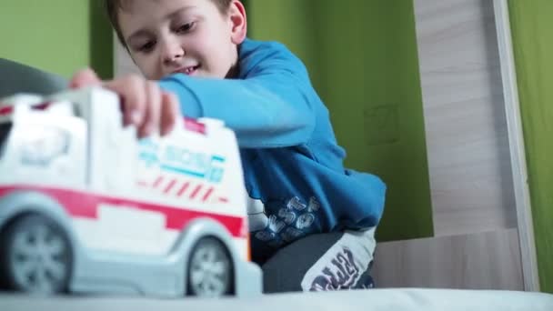 Usměvavý chlapec si hraje se sanitkou na gauči. dětská představivost je hra — Stock video
