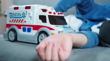Maskeli bir çocuk ambulansla oynuyor. Yalnızlık, çocuksu bir hayal gücü.