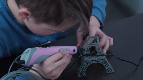 Un niño hace un modelo 3 d con un bolígrafo. ensamblando el diseño de la torre Elfin. clases con rebonk — Vídeo de stock