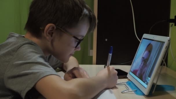 Pelajaran online. seorang anak laki-laki dengan kacamata mendengarkan pelajaran. seorang guru muda menjelaskan program ini — Stok Video