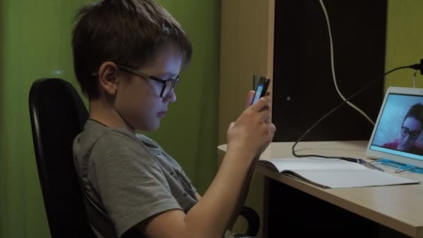 Μάθημα online. Ένας νεαρός δάσκαλος διδάσκει σε μια απομακρυσμένη τοποθεσία. Το αγόρι κρυφοκοιτάζει στο τηλέφωνο. — Αρχείο Βίντεο
