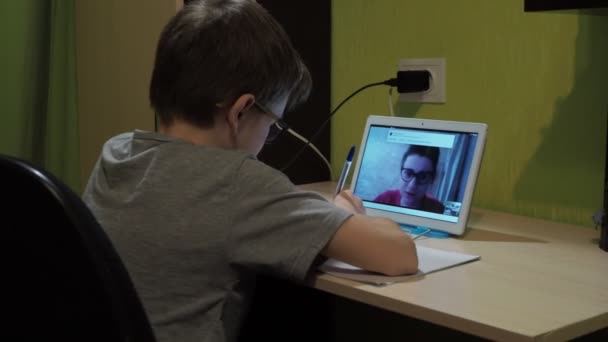 Ders online. Çocuk bir deftere bir görev yazıyor. — Stok video