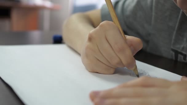Хлопчик у сірій футболці малює олівцями. дитяча рука крупним планом з олівцем — стокове відео