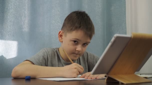 グレーのTシャツを着た少年がタブレットから鉛筆で絵を描いている。アートレッスンをオンラインで — ストック動画