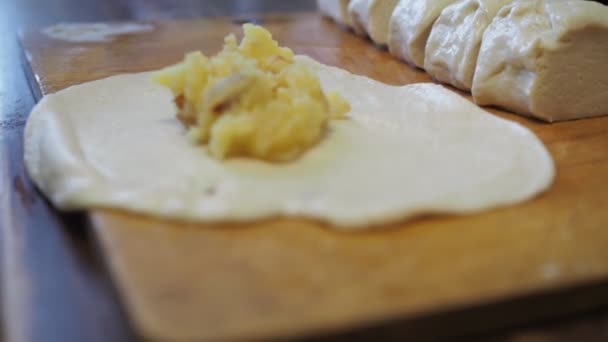 Frauenhände wickeln die Kartoffelfüllung in den Teig. Kuchenbacken in der Küche — Stockvideo