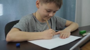 Gri tişörtlü bir çocuk tabletten bir kalemle resim çiziyor. Sanat dersleri çevrimiçi. Kamera resme yakınlaşıyor.