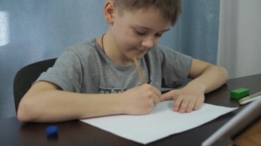 Gri tişörtlü bir çocuk tabletten bir kalemle resim çiziyor. Sanat dersleri çevrimiçi. Kamera resme yakınlaşıyor.