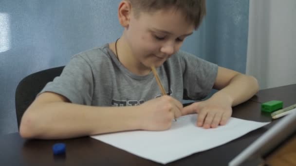 Un niño con una camiseta gris dibuja un cuadro con un lápiz de una tableta. lecciones de arte en línea. la cámara se acerca al dibujo — Vídeo de stock