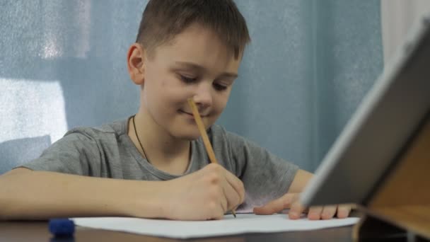 Хлопчик у сірій футболці малює олівцем. посмішка на його обличчі — стокове відео