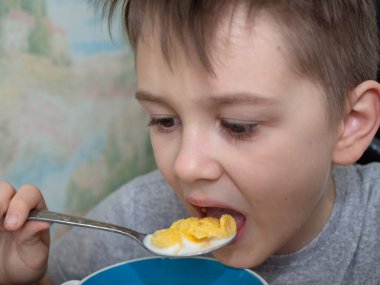 Çocuk mısır gevreğini bir kaşık sütle yiyor. sağlıklı kahvaltı