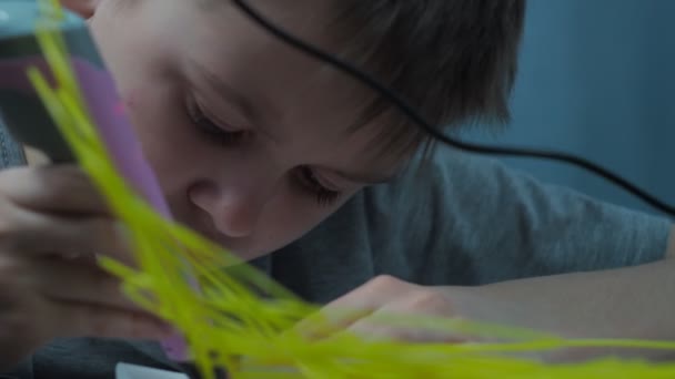 The boy draws 3 d with a yellow pen. close-up of face and pen — Vídeo de Stock
