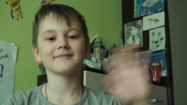 Çocuk kameraya el sallıyor. Seyirciyi selamlar.