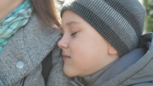 En tioårig pojke ligger på sin mammas axel och kramar henne. uppriktiga barn kärlek — Stockvideo