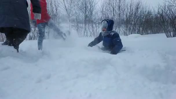 La familia juega bolas de nieve en invierno. el niño está tumbado en la nieve fresca y suave — Vídeos de Stock