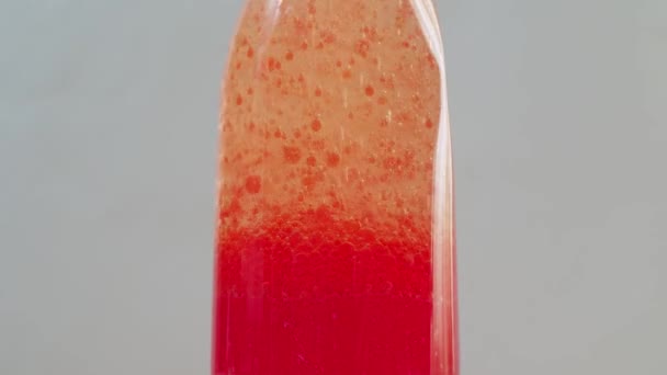 Χημική εμπειρία. στο μπουκάλι, φυσαλίδες κόκκινου χρώματος υψώνονται, που μοιάζουν με τη λάβα ενός ηφαιστείου. οι φυσαλίδες αέρα επάνω — Αρχείο Βίντεο