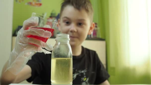 De jongen voert thuis een chemisch experiment uit. voegt een vloeistof met een kleurstof toe aan de oliefles. een jonge chemicus — Stockvideo