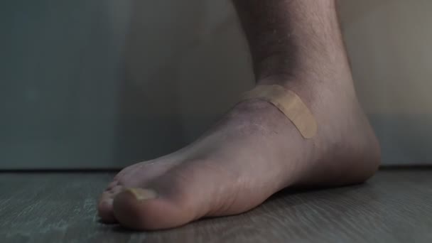 Muž odstraní náplast z rány na noze. nepohodlné boty — Stock video