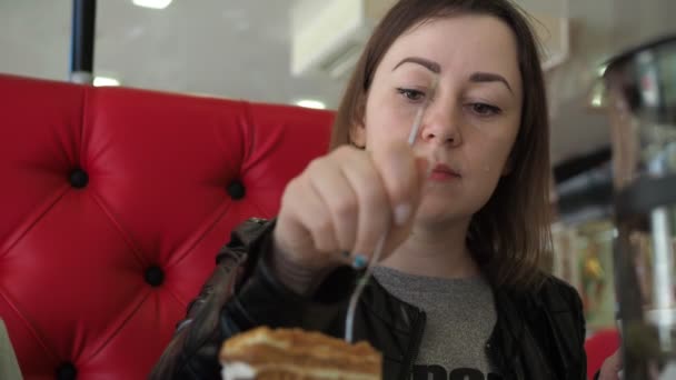 Mladá žena se usměje a sní dort v kavárně. detailní záběr obličeje — Stock video