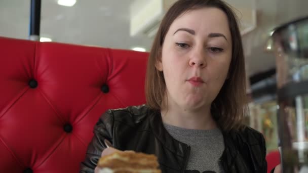 Młoda kobieta w kawiarni je śniadanie i pije herbatę. zbliżenie twarzy — Wideo stockowe
