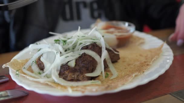 Mujer joven comiendo carne en un restaurante con un plato — Vídeo de stock