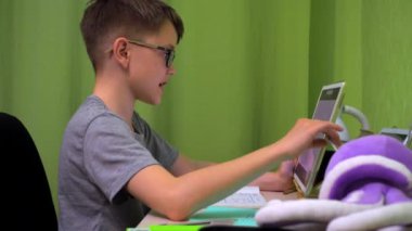 Online ders. Çocuk öğretmenlerin sorularını cevaplıyor. Tablet ekranındaki yanıtları kaydeder