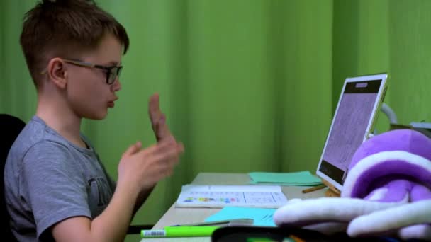 Online lekce. chlapec píše odpovědi na otázky na obrazovce tabletu. a on mluví, gestikuluje rukama — Stock video