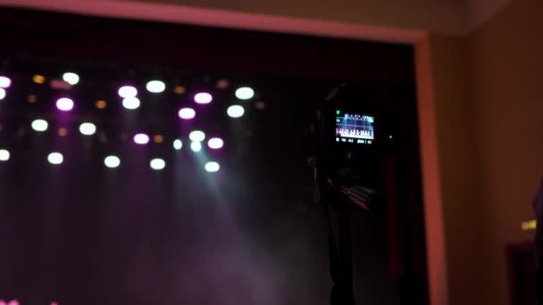 Uma câmera DSLR em um tripé captura o concerto. uma mão de homem ajusta a câmera. gravação de vídeo — Vídeo de Stock