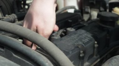 Bir adam arabanın motorundaki yüksek voltajlı kabloları söker. Arabanın kaputunun altında çalış. Mumlar değiştiriliyor