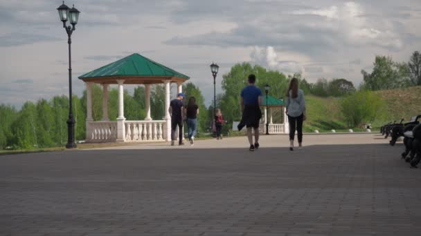 Parejas caminan por el terraplén. La primavera está afuera. gazebos y bancos para la recreación. juntos. desde atrás — Vídeo de stock