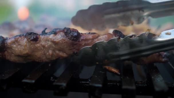 Cocinar costillas de cerdo a la parrilla con cebolla. una mano de hombre gira las costillas con tongs.close-up — Vídeos de Stock