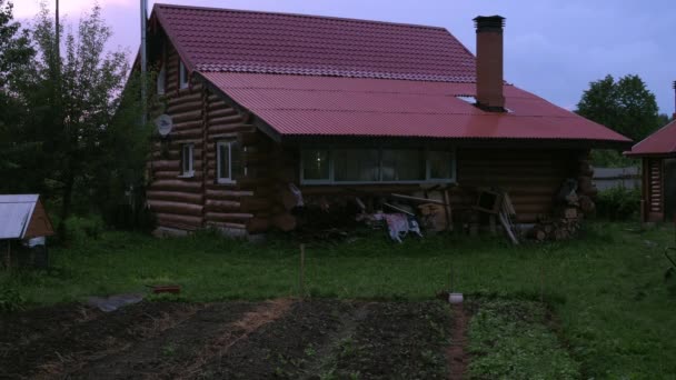 Maison en bois rond. pluie d'été. une parcelle de terrain par temps sombre — Video