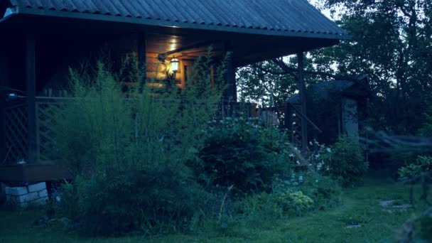 Hořící světlo na venkovský dům v zeleni stromů. Ve světle létá hmyz. léto — Stock video