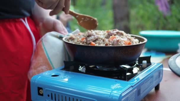 Kochen von Lebensmitteln auf einem Campingkocher. Fleisch in einer Pfanne auf einem Campingtisch. Zelten. Freizeitgestaltung im Freien — Stockvideo