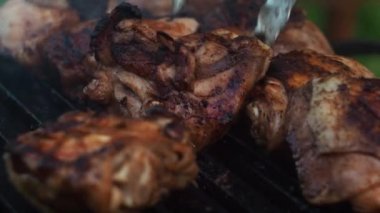 Maşayla, tavuk butlarını ızgaraya çeviriyor. Kızarmış tavuk. ızgaranın ortasına odaklan
