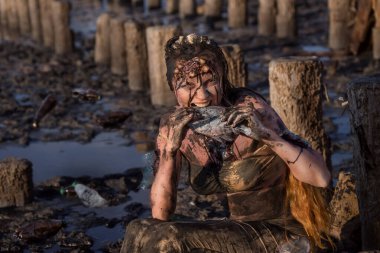 Deniz çevresinin plastik kirliliği ve koruma kavramı - yakıt yağına bulanmış bitkin ve yaralı bir denizkızı, çamur ve enkazdan muzdarip ve kirli balık yiyor.