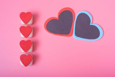 Sol tarafta dikey olarak dört kırmızı kalp, pembe arka plan. Sevgililer gününde aşk ve mutluluk kavramı.