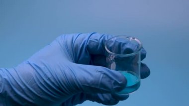 Mavi bir sıvı küçük bir şişeden bir pipetle alınır. Tıbbi araştırma ve geliştirme kavramı.