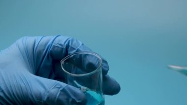 Mavi bir sıvı küçük bir şişeden bir pipetle alınır. Tıbbi araştırma ve geliştirme kavramı.