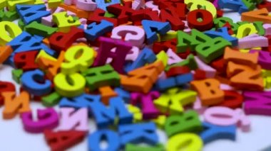 Çok renkli ahşap harfler beyaz bir arkaplanda dönüyor. Bir sürü renkli harf, alfabe gibi..