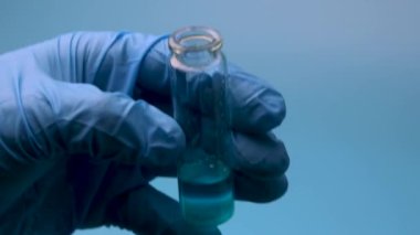 Mavi bir sıvı küçük bir şişeden bir pipetle alınır. Tıbbi araştırma ve geliştirme kavramı.
