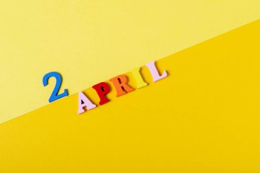 Tahta harfler 2 Nisan 'da sarı arka planda. Uluslararası Çocuk Kitapları Günü.