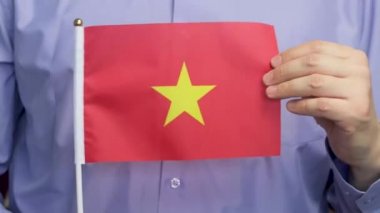 Bir adam açık havada Vietnam bayrağını tutuyor. Bayrağı salla ve elini kaldır..