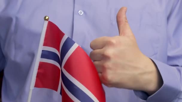 青いシャツの背景にノルウェーの旗を振って 男の手の中にノルウェーの旗 ノルウェーの誇り — ストック動画
