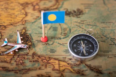 Palau bayrağı, dünya haritasında pusula ve uçak. Turizm ve eğlence kavramı..
