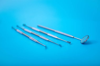 Dişçinin tıbbi gereçleri. Mavi zemin üzerinde paslanmaz çelik dişçi ekipmanı.