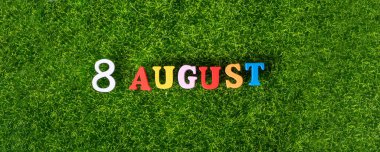 August 8. Image of wooden colored letters and numbers on August 8 against the background of a green lawn, World Cat Day. A summer day. Empty space for the text.